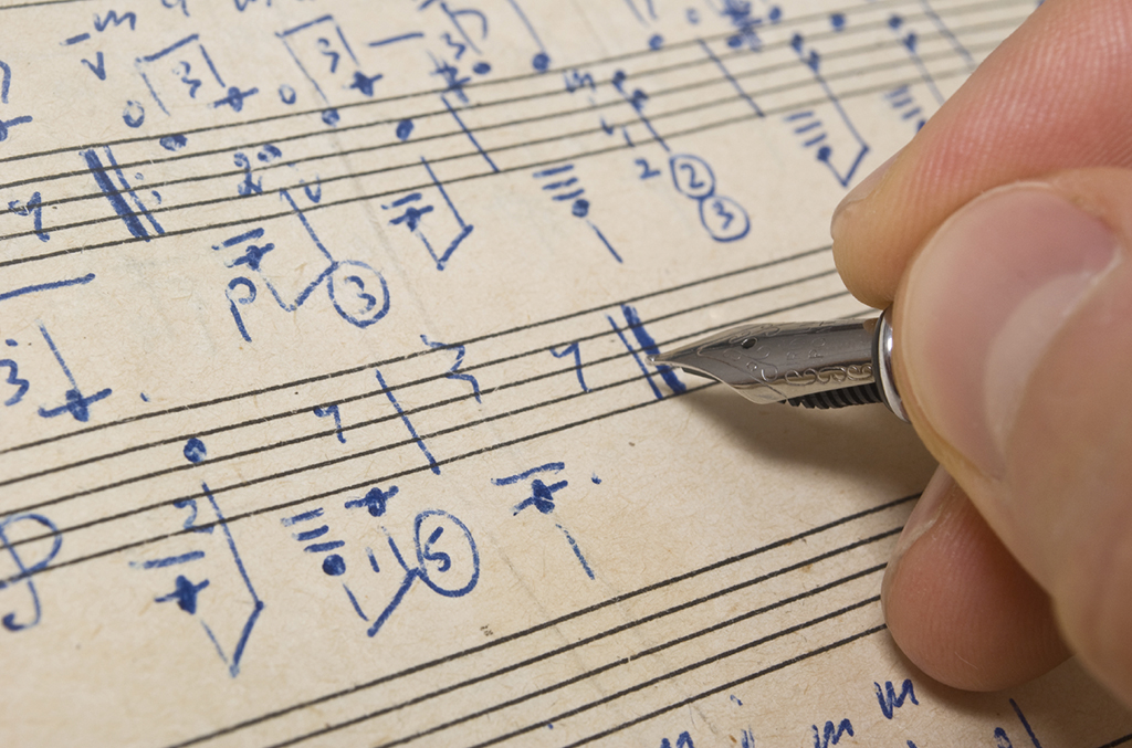Hand with pen and music sheet - musical background